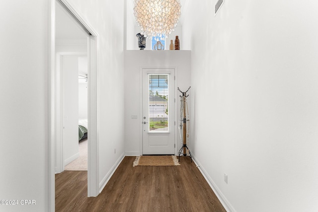 doorway featuring a high ceiling, an inviting chandelier, and dark hardwood / wood-style flooring