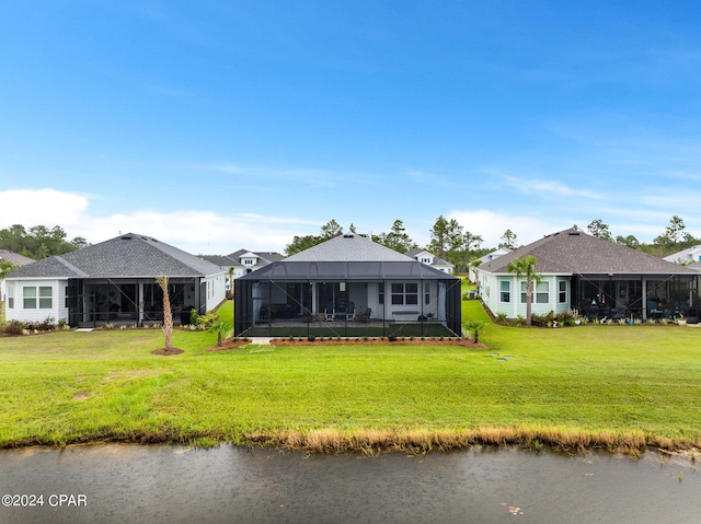 rear view of house with a lawn, a lanai, and a water view