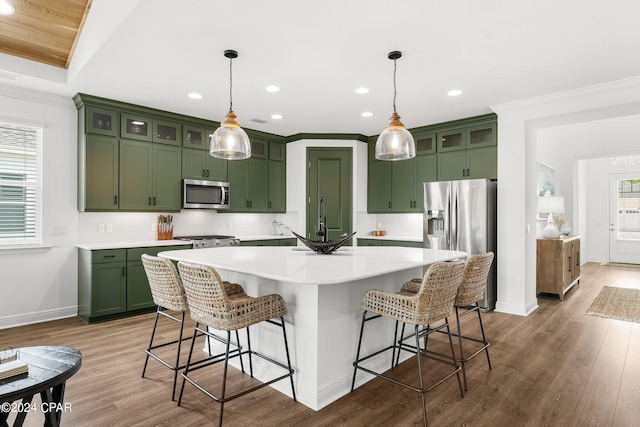 kitchen featuring stainless steel appliances, green cabinetry, and decorative light fixtures