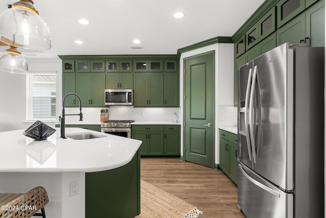 kitchen featuring pendant lighting, green cabinets, stainless steel appliances, decorative backsplash, and sink