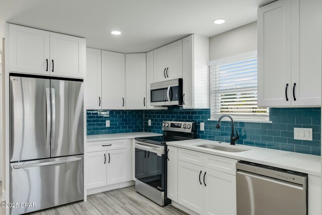 kitchen featuring white cabinetry, sink, stainless steel appliances, and light wood-type flooring