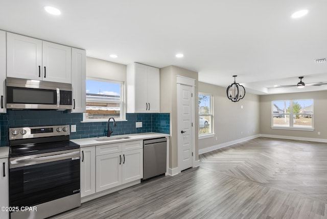 kitchen featuring ceiling fan with notable chandelier, white cabinetry, sink, stainless steel appliances, and plenty of natural light