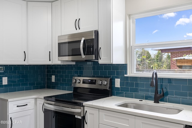 kitchen with white cabinetry, appliances with stainless steel finishes, sink, and decorative backsplash