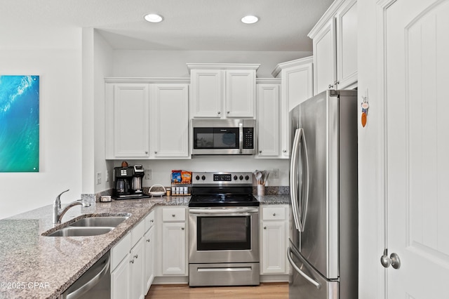 kitchen featuring white cabinetry, stainless steel appliances, sink, and light stone counters