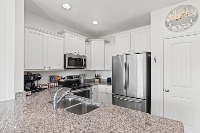 kitchen featuring stainless steel appliances, white cabinetry, sink, and light stone counters