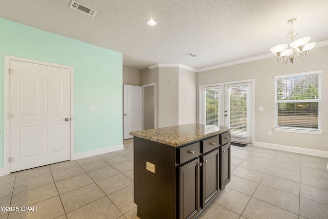 kitchen featuring a center island, a textured ceiling, light tile patterned floors, pendant lighting, and light stone countertops