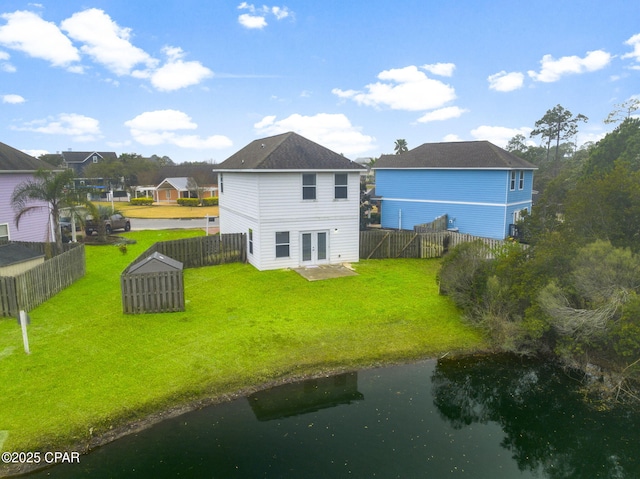 rear view of house with a water view, a yard, and french doors