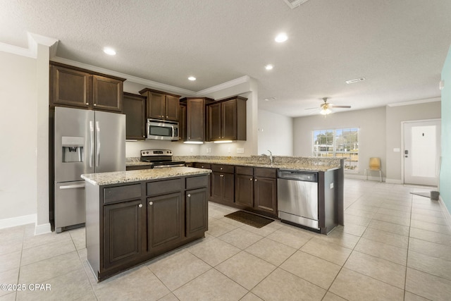 kitchen with light tile patterned flooring, kitchen peninsula, stainless steel appliances, crown molding, and dark brown cabinets