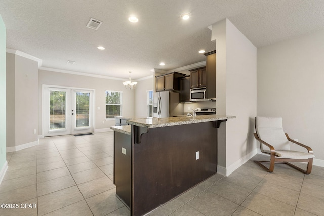 kitchen with light tile patterned flooring, appliances with stainless steel finishes, a breakfast bar area, ornamental molding, and kitchen peninsula