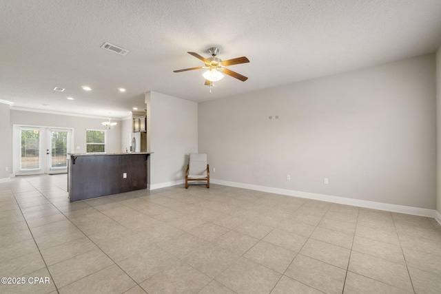 unfurnished room featuring light tile patterned floors, ornamental molding, a textured ceiling, ceiling fan with notable chandelier, and french doors