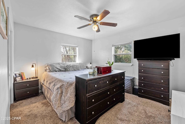 bedroom with a ceiling fan, light colored carpet, and multiple windows