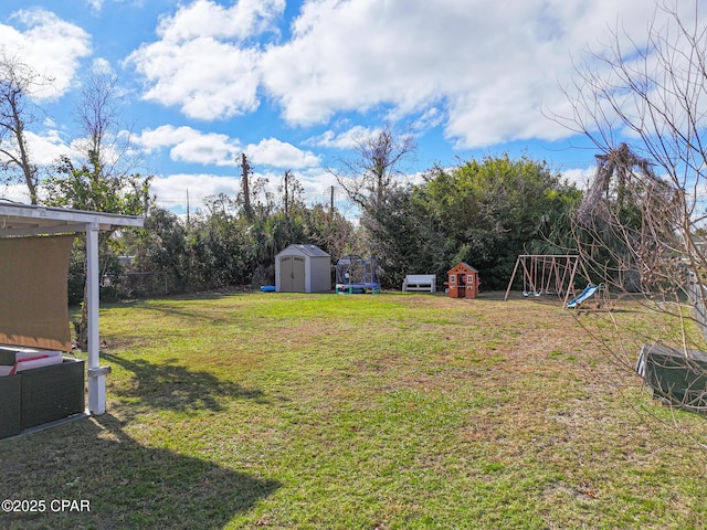 view of yard featuring a storage shed, a trampoline, fence, an outdoor structure, and a playground