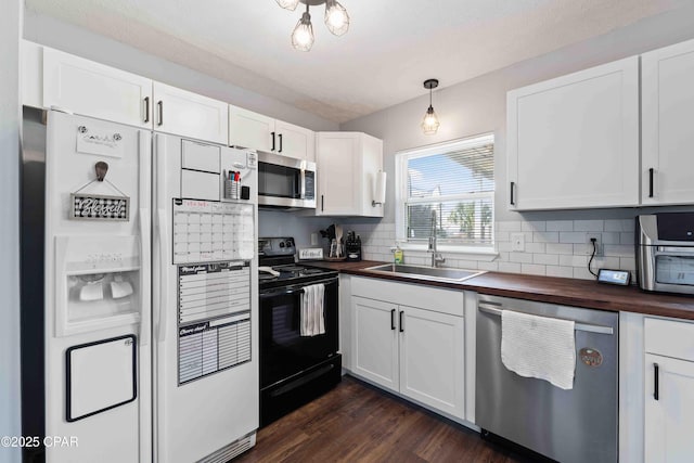 kitchen with wood counters, a sink, stainless steel appliances, white cabinetry, and backsplash