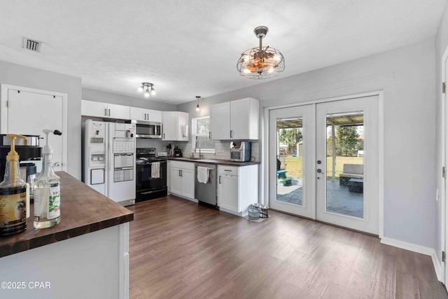 kitchen featuring wood counters, visible vents, white cabinets, appliances with stainless steel finishes, and decorative light fixtures