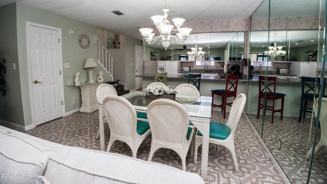 dining space with a textured ceiling and an inviting chandelier