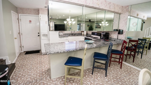 kitchen featuring white gas range, kitchen peninsula, and sink