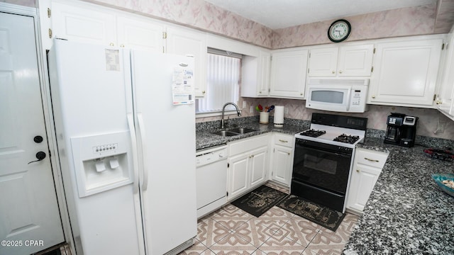 kitchen featuring white cabinetry, sink, dark stone counters, and white appliances