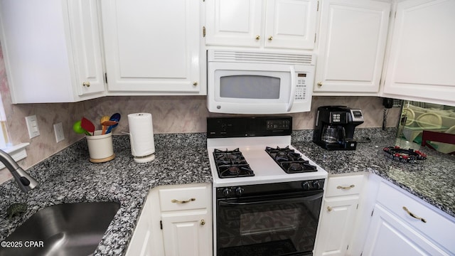 kitchen featuring white cabinetry, sink, dark stone countertops, white appliances, and decorative backsplash