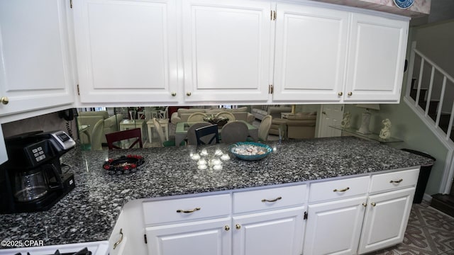 kitchen featuring dark stone countertops, white cabinetry, and range