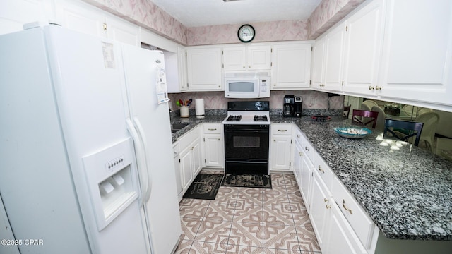 kitchen featuring white cabinets, white appliances, and dark stone counters