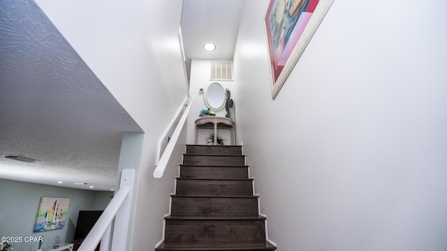 stairway featuring a textured ceiling