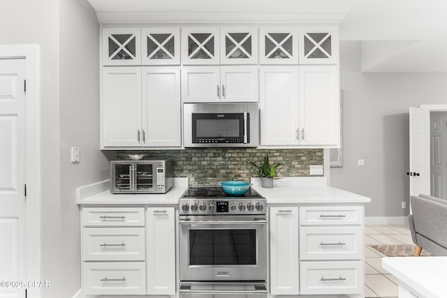 kitchen with decorative backsplash, light tile patterned floors, white cabinets, and stainless steel appliances