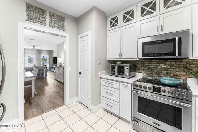 kitchen with light tile patterned floors, decorative backsplash, stainless steel appliances, and white cabinetry