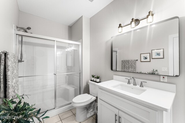 bathroom featuring toilet, tile patterned flooring, a shower with shower door, and vanity