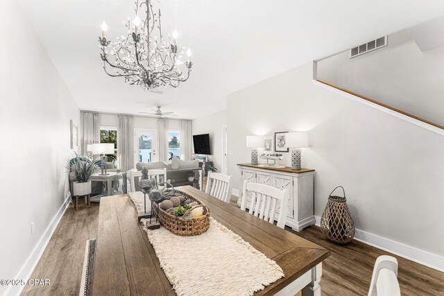 dining space with ceiling fan with notable chandelier and dark hardwood / wood-style floors