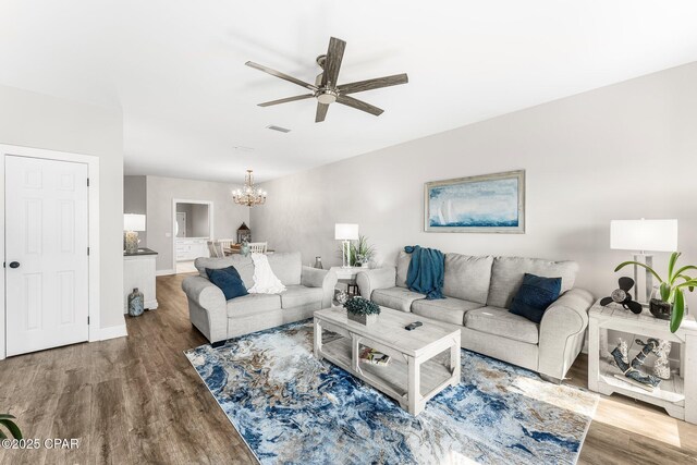 living room featuring ceiling fan with notable chandelier and wood-type flooring