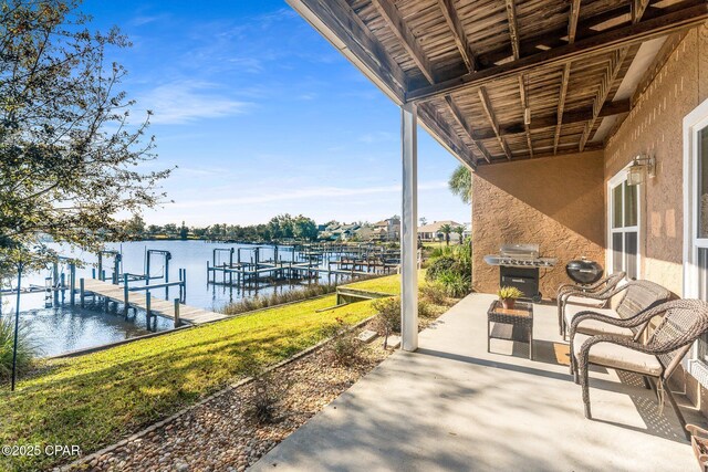 view of dock with a water view, a lawn, and a patio