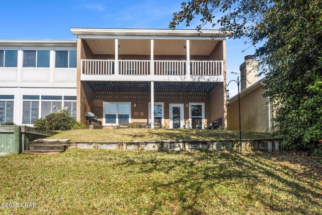 rear view of property with a balcony and a yard