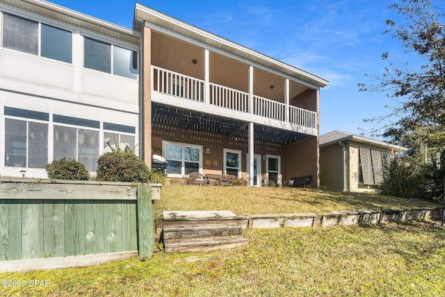 rear view of house with a balcony and a yard