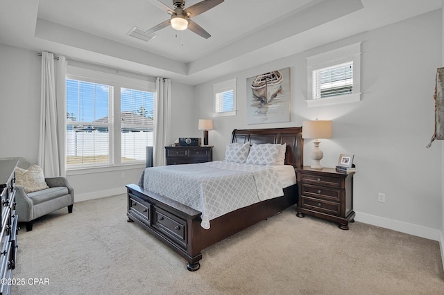 carpeted bedroom featuring ceiling fan, a tray ceiling, and a water view