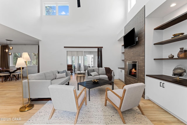 living room featuring a fireplace, a high ceiling, and light hardwood / wood-style flooring