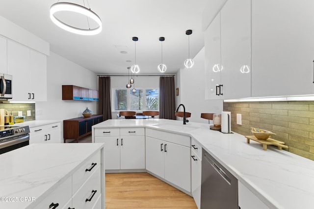 kitchen with pendant lighting, sink, decorative backsplash, white cabinetry, and stainless steel appliances