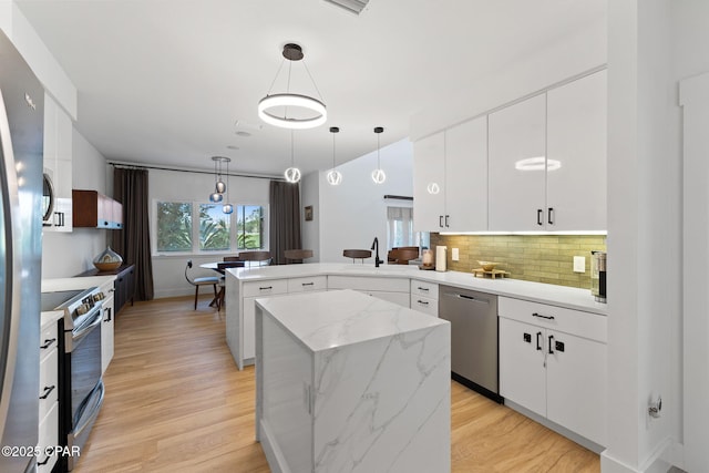 kitchen with white cabinets, a kitchen island, pendant lighting, and appliances with stainless steel finishes