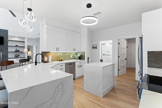 kitchen with hanging light fixtures, white cabinets, stainless steel appliances, and light hardwood / wood-style floors