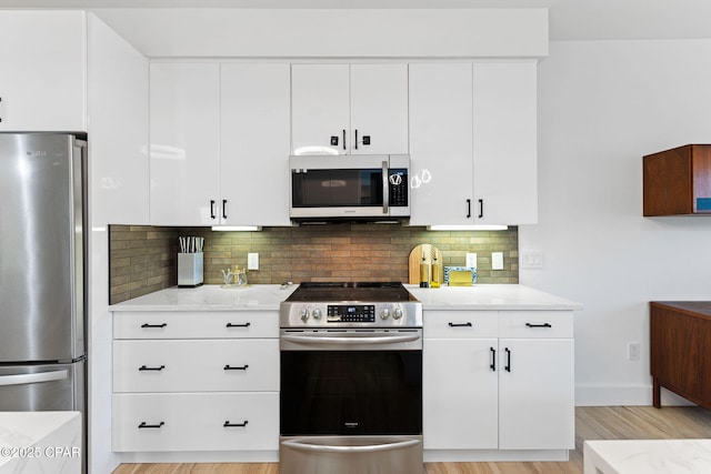 kitchen featuring white cabinets, light stone countertops, stainless steel appliances, and tasteful backsplash