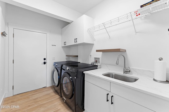 clothes washing area with cabinets, independent washer and dryer, light wood-type flooring, and sink