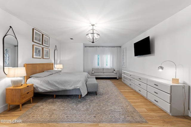 bedroom with light hardwood / wood-style floors and an inviting chandelier