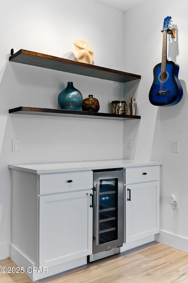 bar featuring white cabinets, beverage cooler, and light hardwood / wood-style flooring