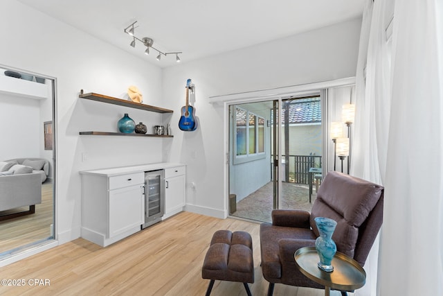 sitting room featuring wine cooler, light hardwood / wood-style flooring, and indoor bar