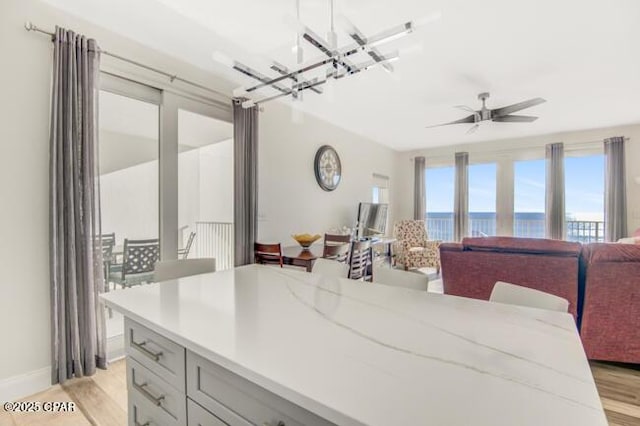 interior space featuring light stone countertops, pendant lighting, light hardwood / wood-style flooring, and ceiling fan