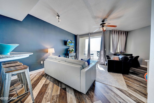 living room featuring ceiling fan, wood-type flooring, expansive windows, and a textured ceiling