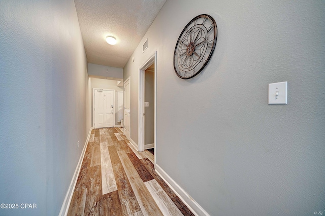 hallway featuring light wood-type flooring and a textured ceiling