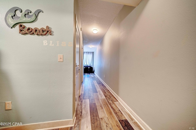 hall with a textured ceiling and wood-type flooring