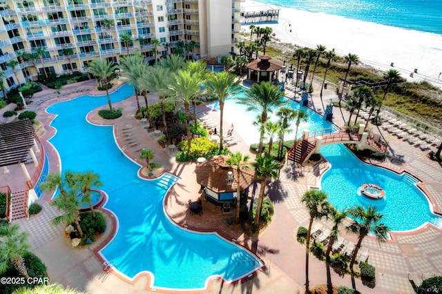 view of swimming pool featuring a beach view, a water view, and a gazebo