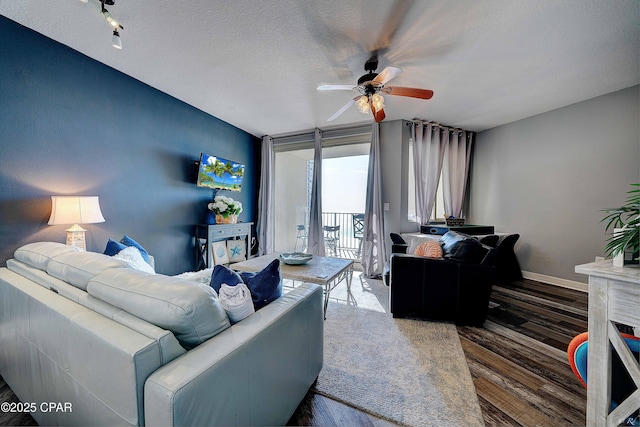 living room with a textured ceiling, dark wood-type flooring, a wall of windows, and ceiling fan