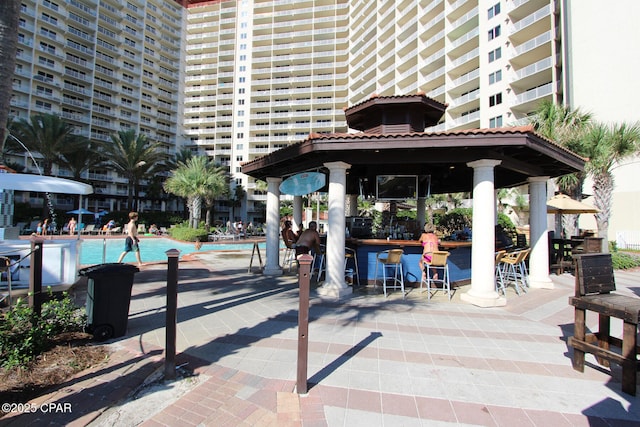 view of community with a pool, a gazebo, a bar, and a patio area